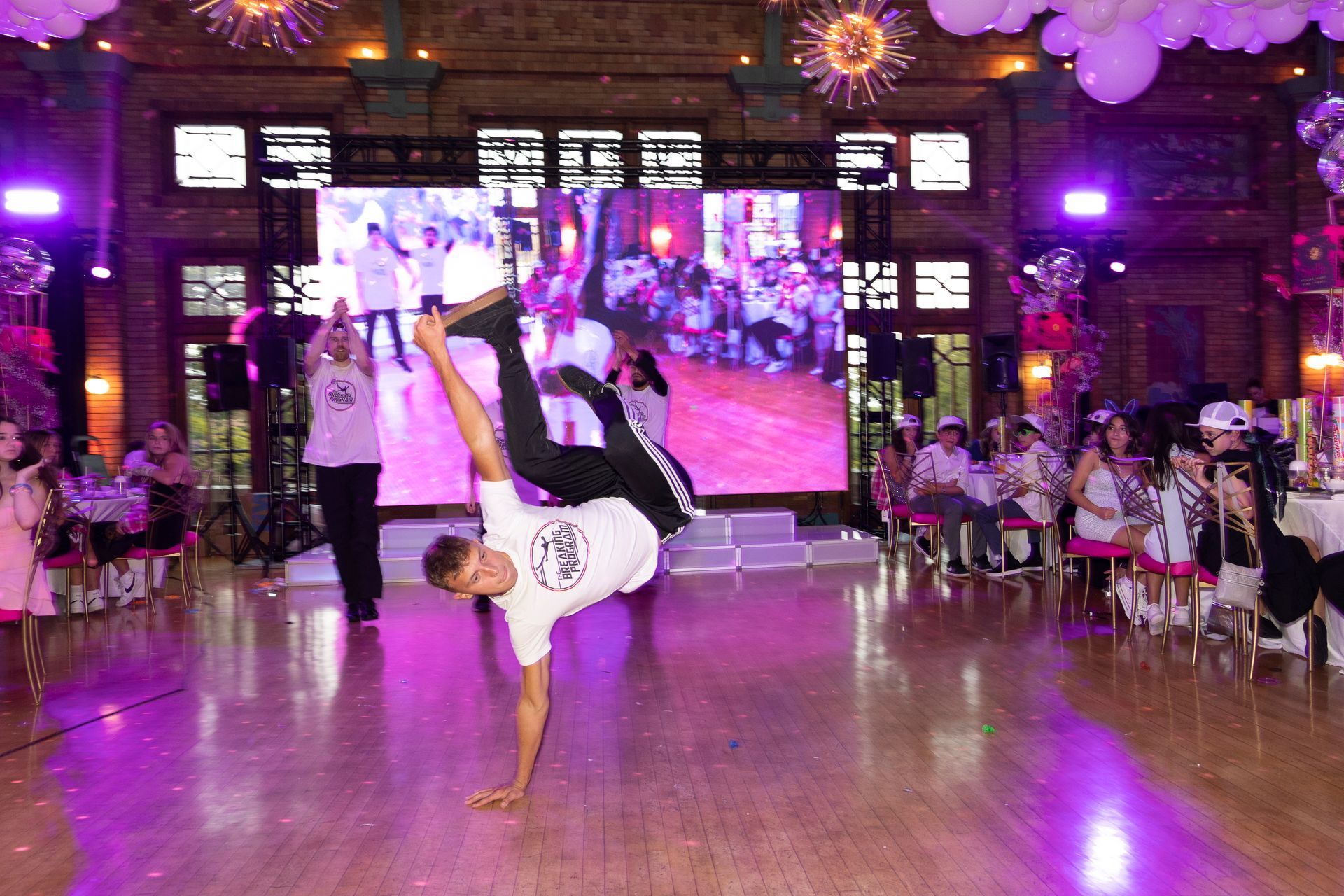 A man is doing a handstand on a dance floor at a party.