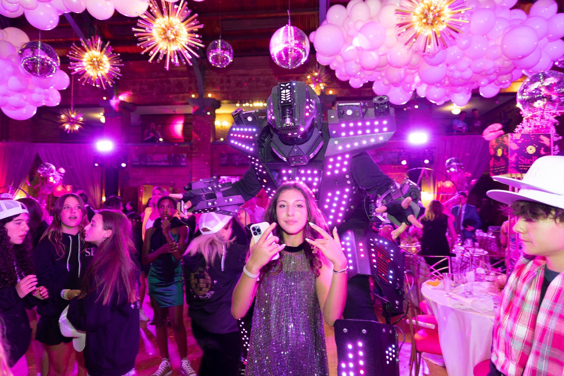 A girl is standing in front of a robot at a party.