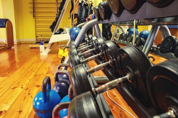 File di manubri e kettlebell in una palestra ben illuminata con pavimenti in legno lucido.