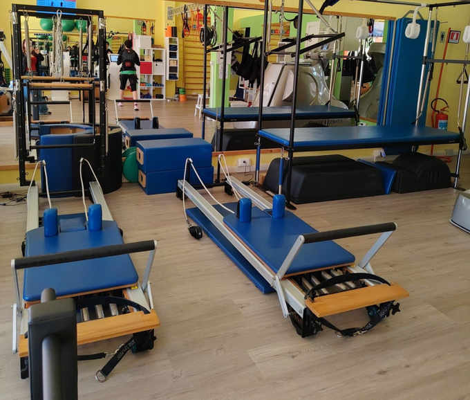 Attrezzature per l'esercizio fisico in una palestra luminosa con pareti verdi e un tapis roulant in primo piano.