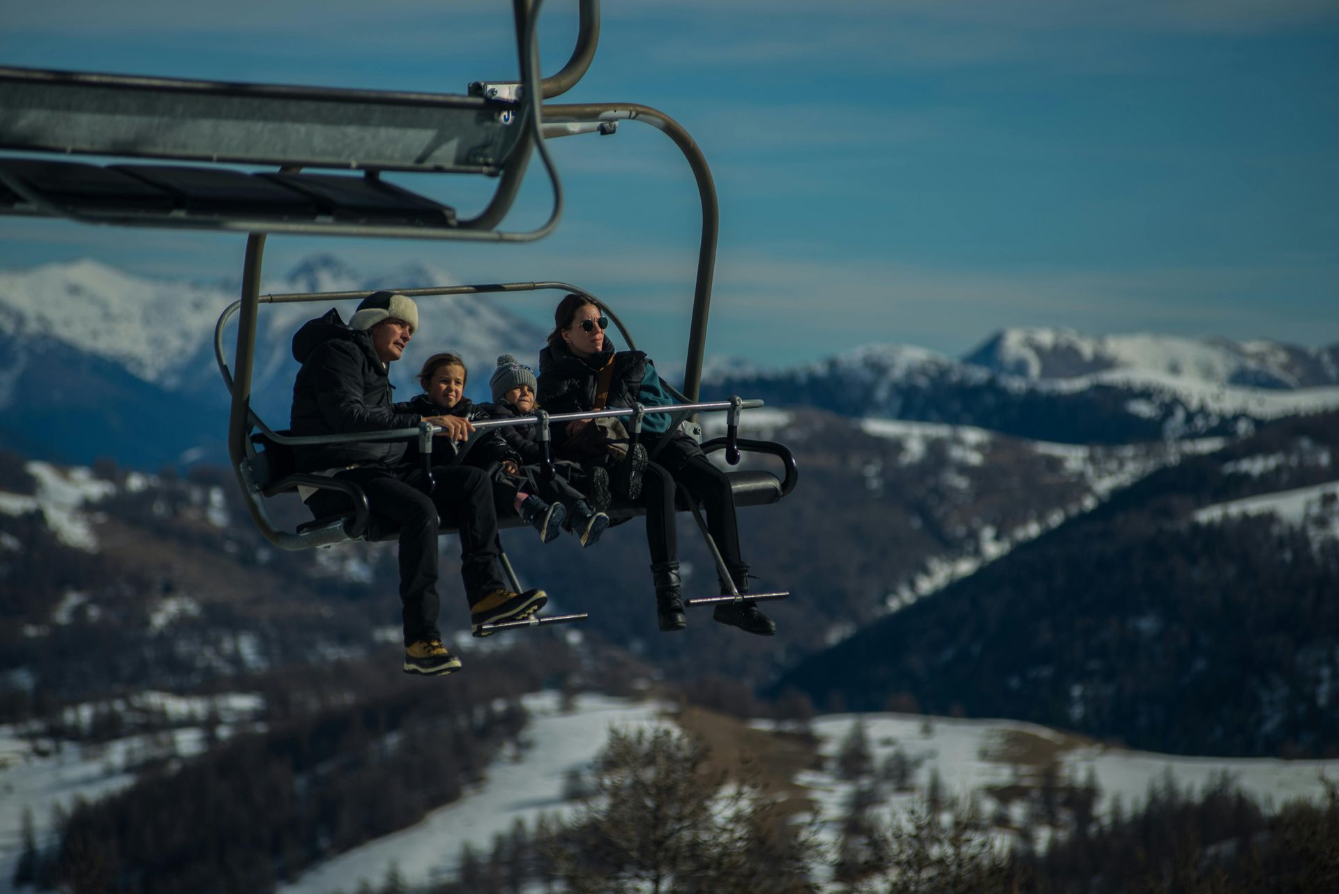 A group of people are riding a ski lift in the mountains.
