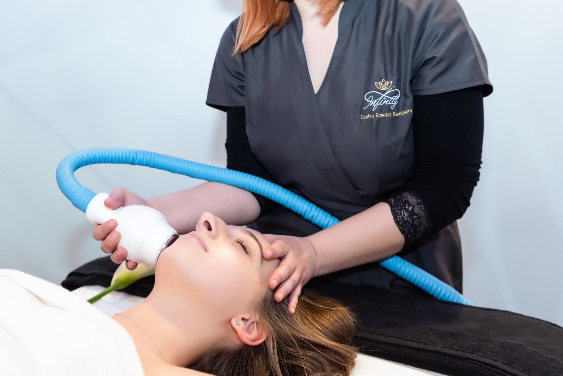Un medico utilizza un dispositivo laser cosmetico portatile sulla mandibola di un cliente sdraiato su un lettino da spa.