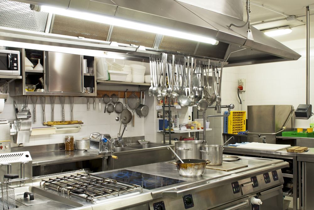 A Kitchen With a Large Island, Sink, Refrigerator and Stainless Steel Appliances — Commercial Kitchens Direct in Unanderra, NSW