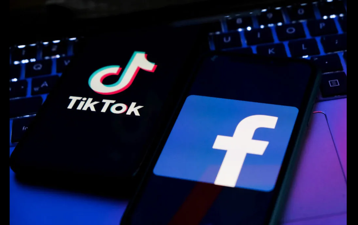 TikTok and Facebook app logos on a keyboard, lit in blue and purple tones
