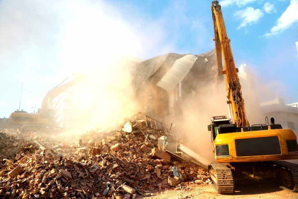 A large yellow excavator is demolishing a building.