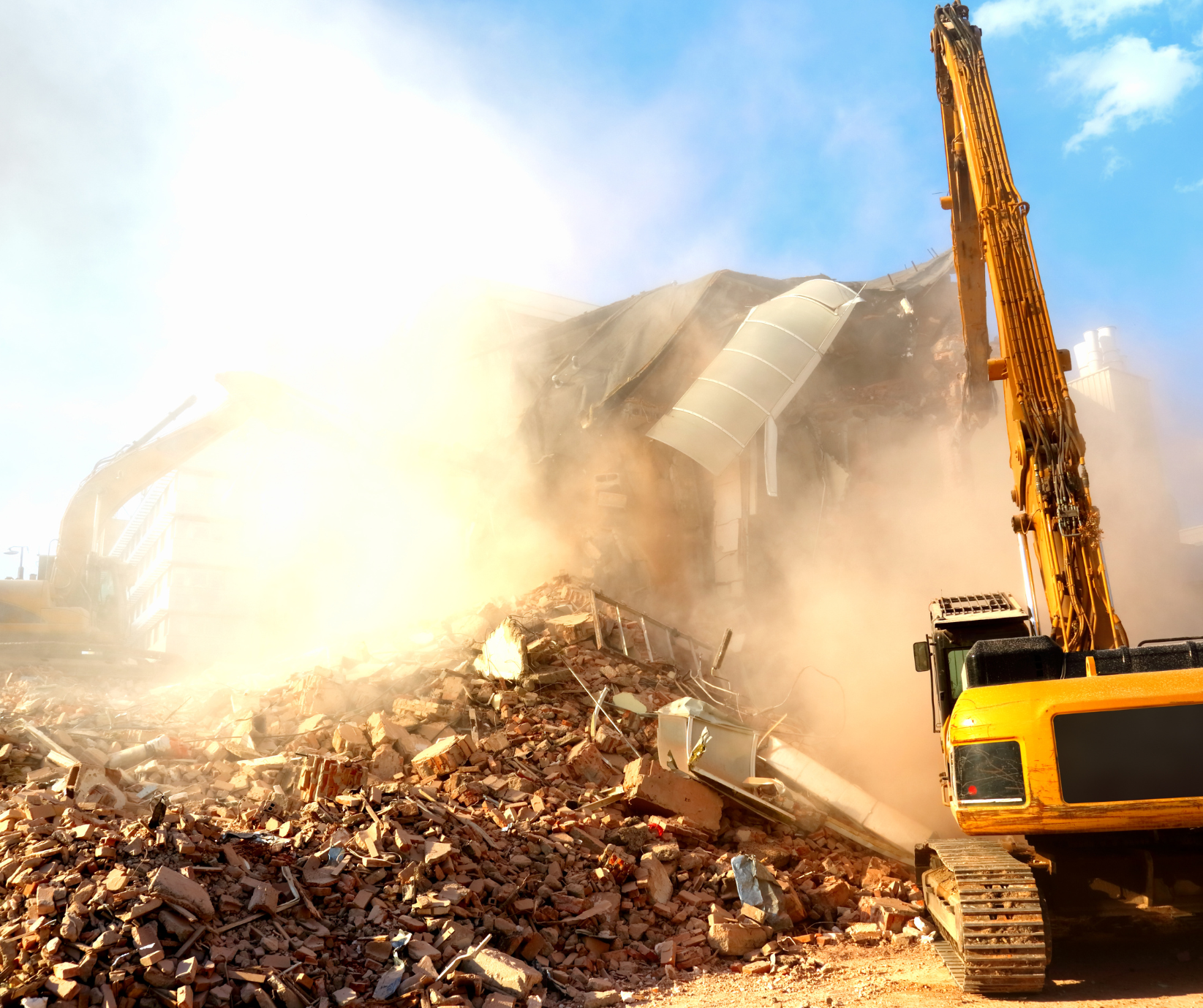 A large yellow excavator is demolishing a building.