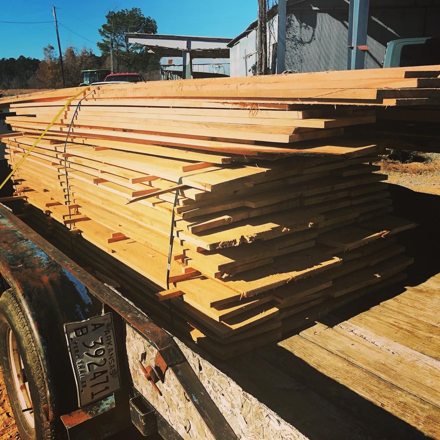 A stack of wood sits on top of a trailer with a texas license plate