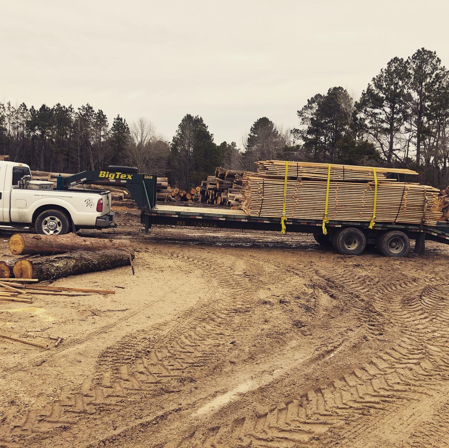 A white truck is pulling a trailer full of logs