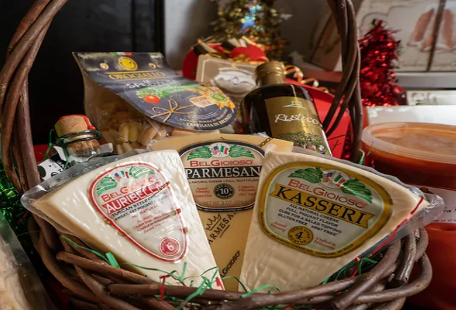A basket filled with different types of cheese and a bottle of wine.