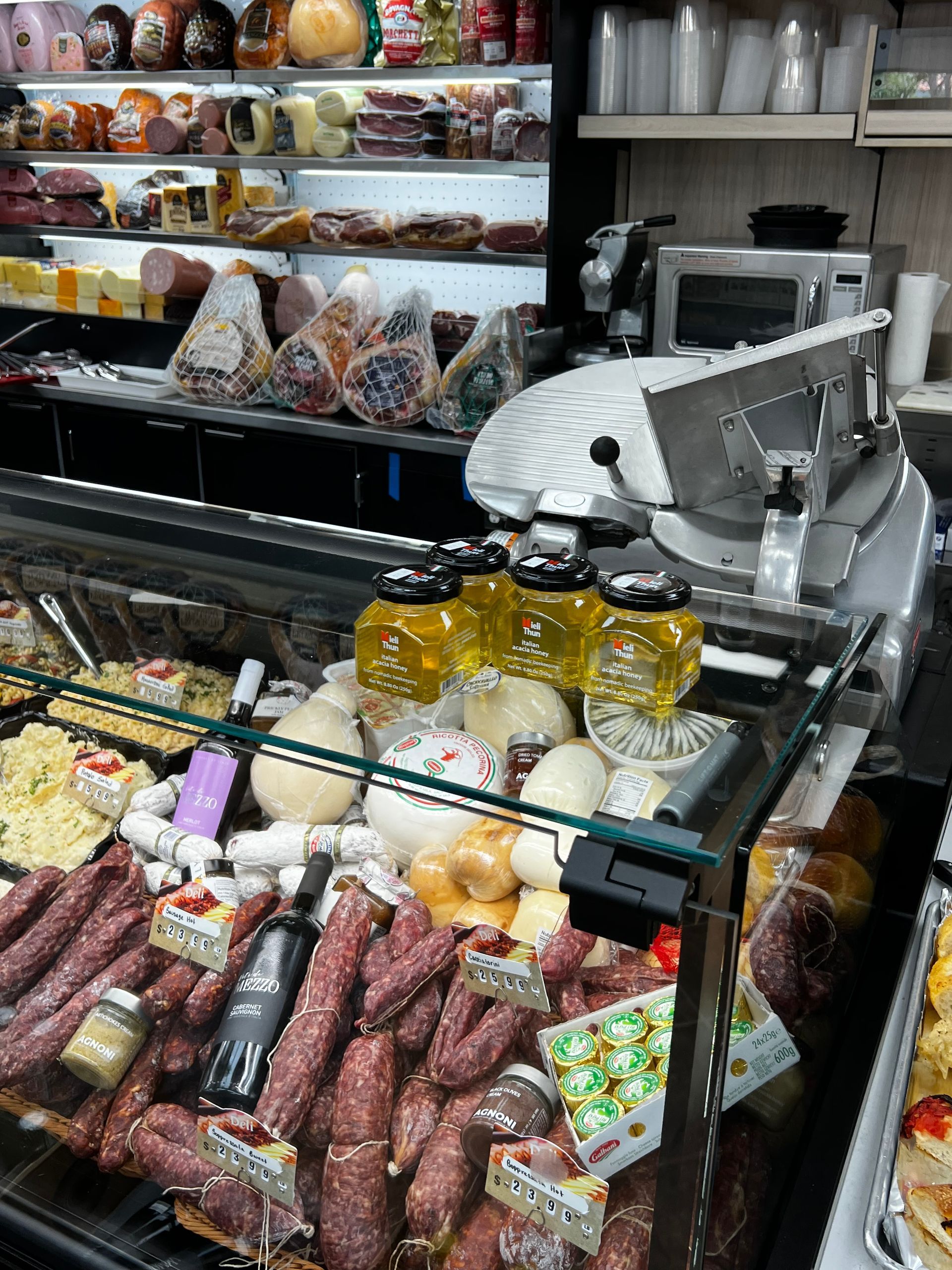 A variety of meats and cheeses are displayed in a store.
