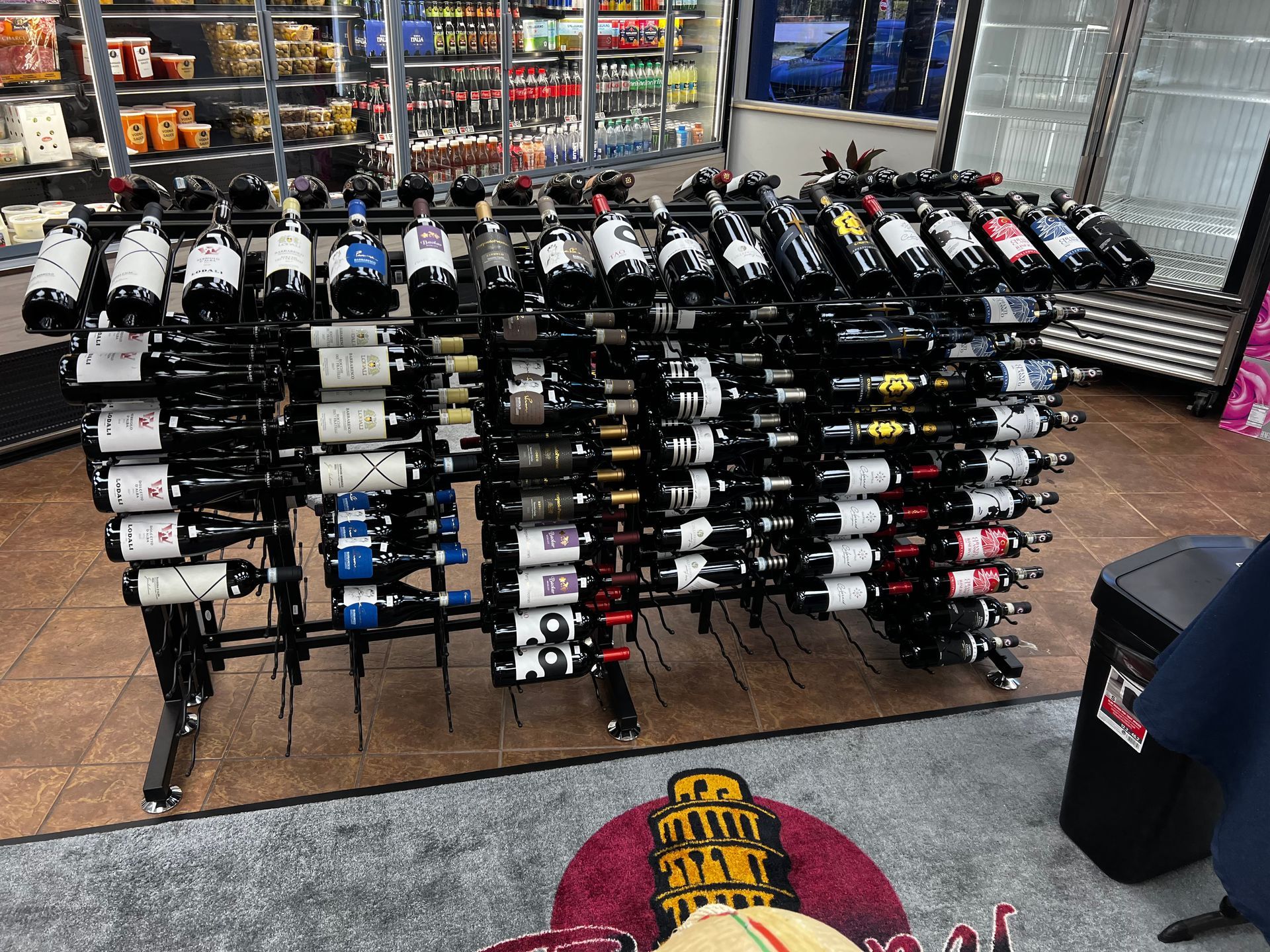 A bunch of wine bottles are lined up on a rack in a store