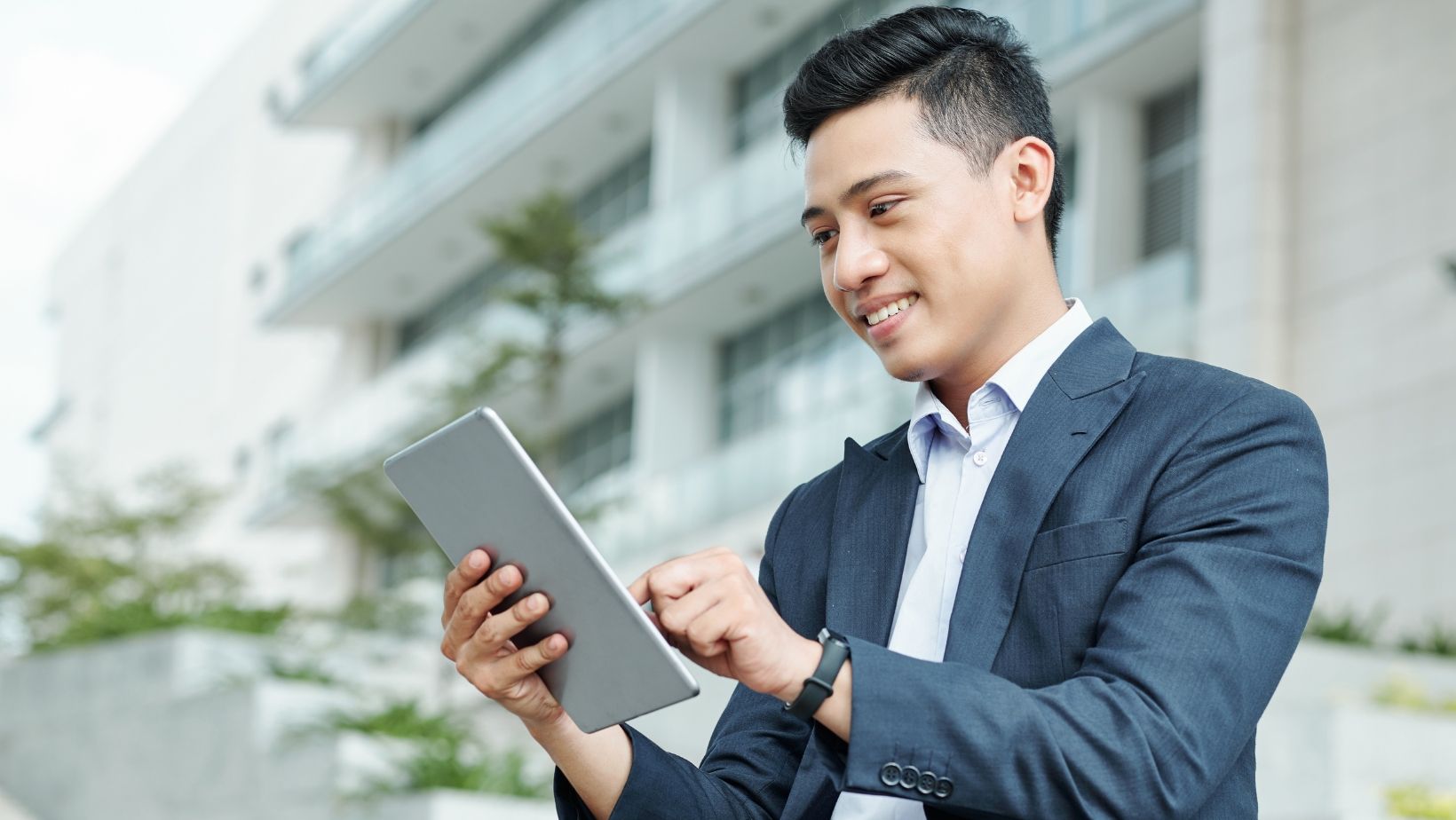 A man in a suit is using a tablet computer.