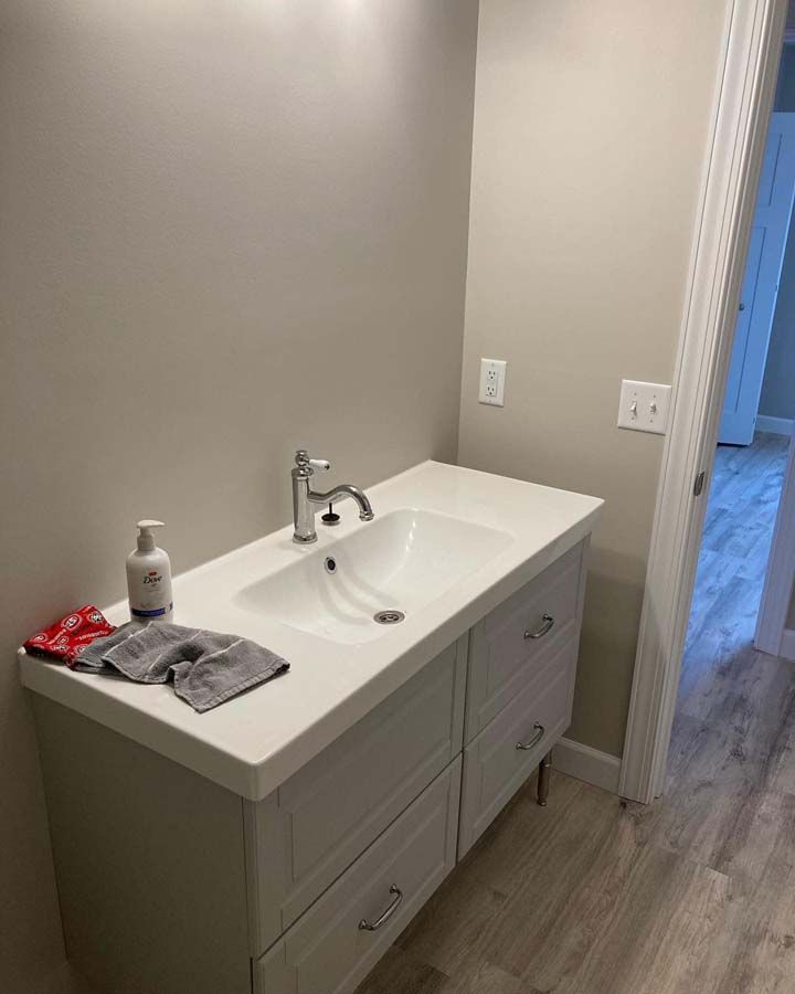 Small bathroom vanity with sink, mirror, soap dispenser, and towels on a white countertop.
