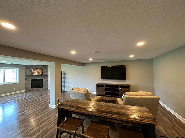 Spacious living room with TV, fireplace, wood flooring, and dining table in foreground