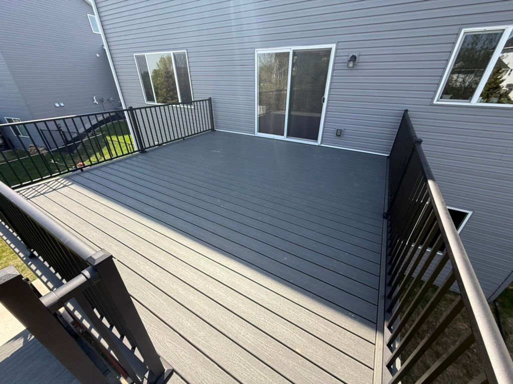 Empty gray composite deck with black railings beside a gray house exterior