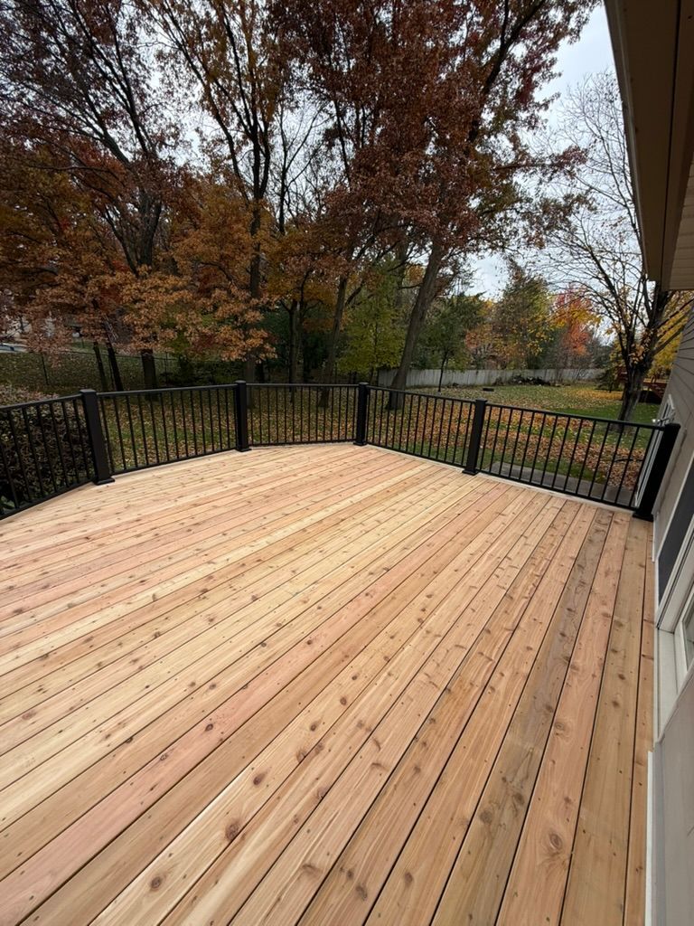 Freshly built wooden deck with black railings overlooking autumn trees