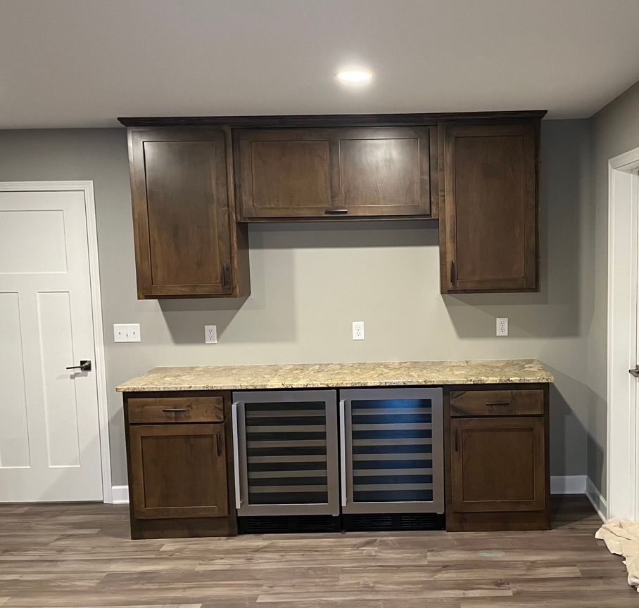 Built-in dark wood cabinets and wine cooler in a modern kitchen nook with light countertops and gray walls