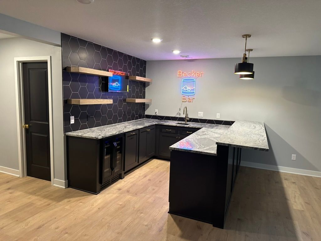 Modern kitchen with black cabinets, granite countertops, pendant light, and light wood flooring