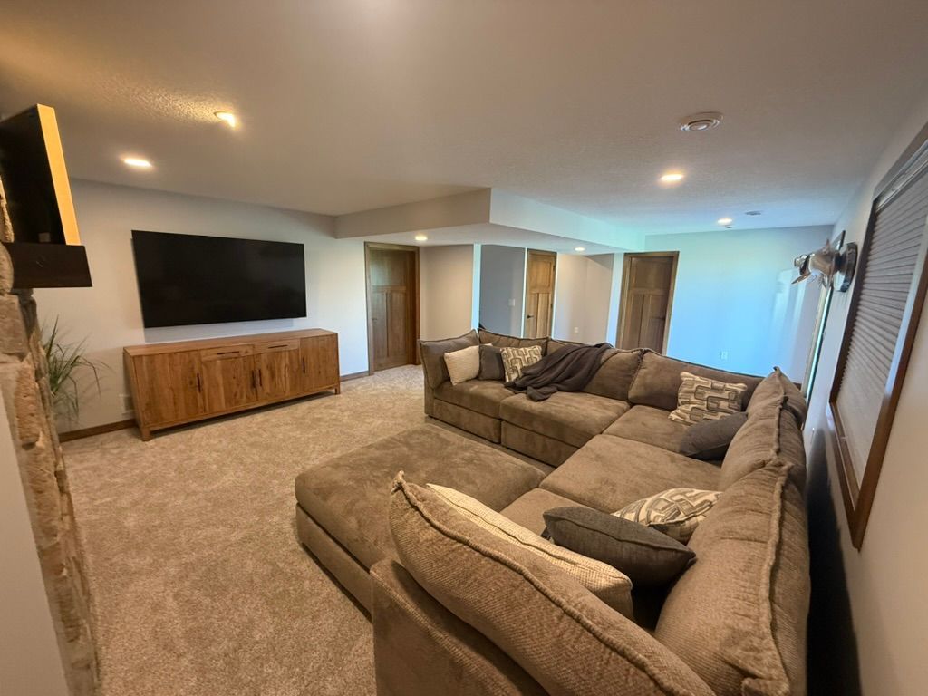 Spacious living room with a large sectional sofa, wall-mounted TV, and wood console in neutral tones.