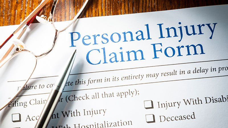 Glasses and Pen lying on Personal injury claim form