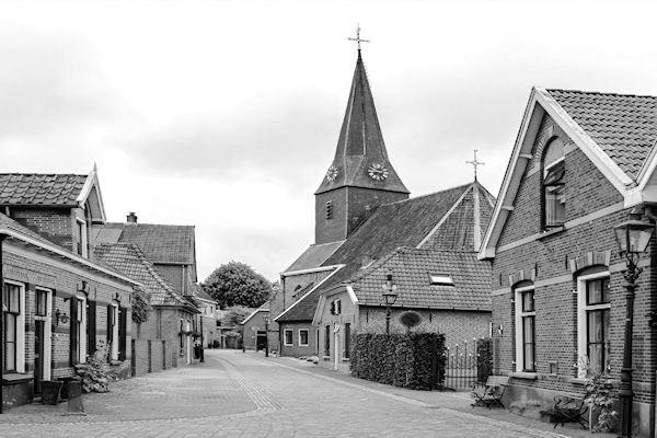 Een zwart-witfoto van een dorp met een kerk op de achtergrond.