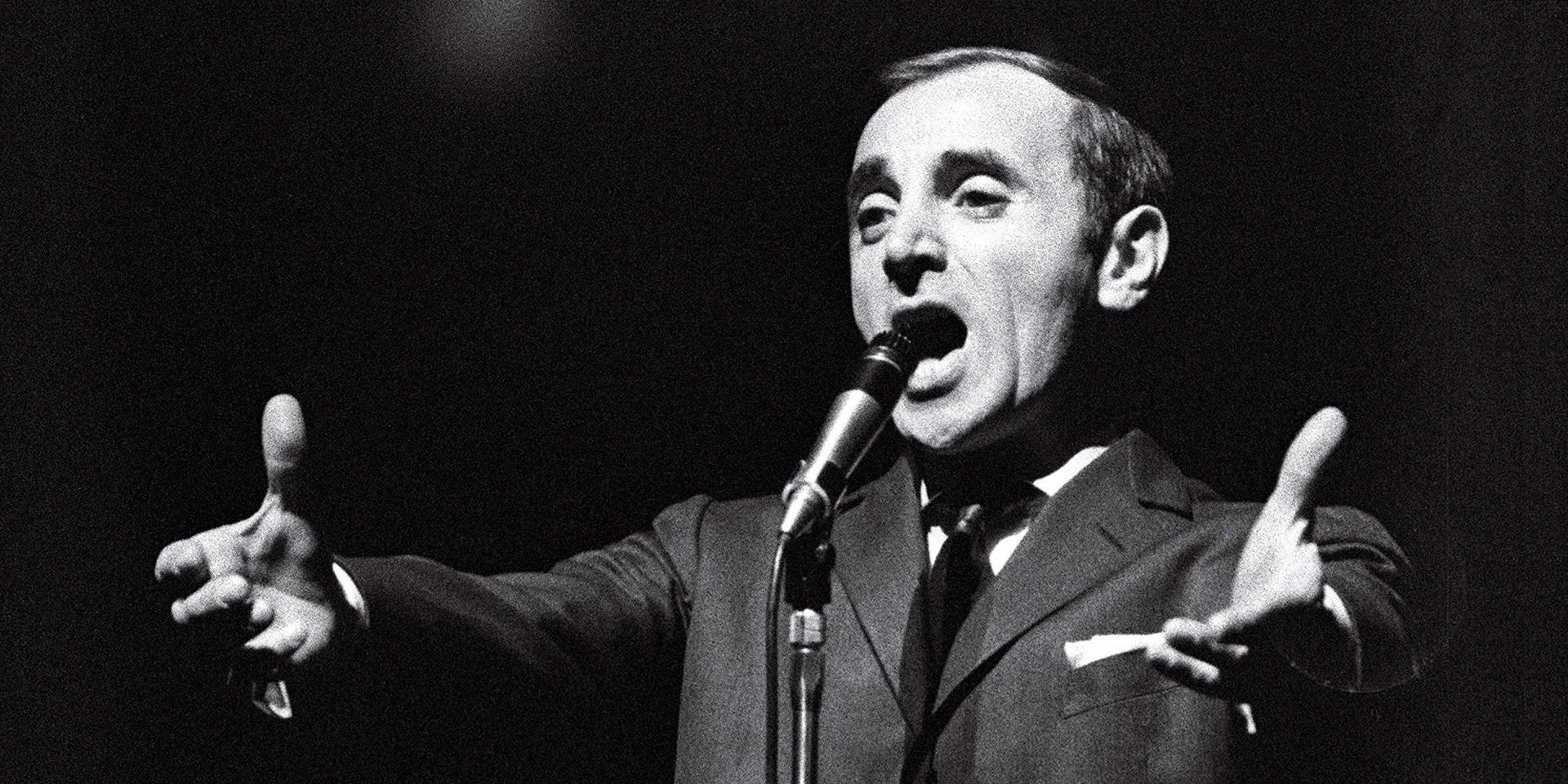 Een man in pak en stropdas zingt in een microfoon.