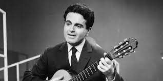 Een man in pak en stropdas speelt gitaar.