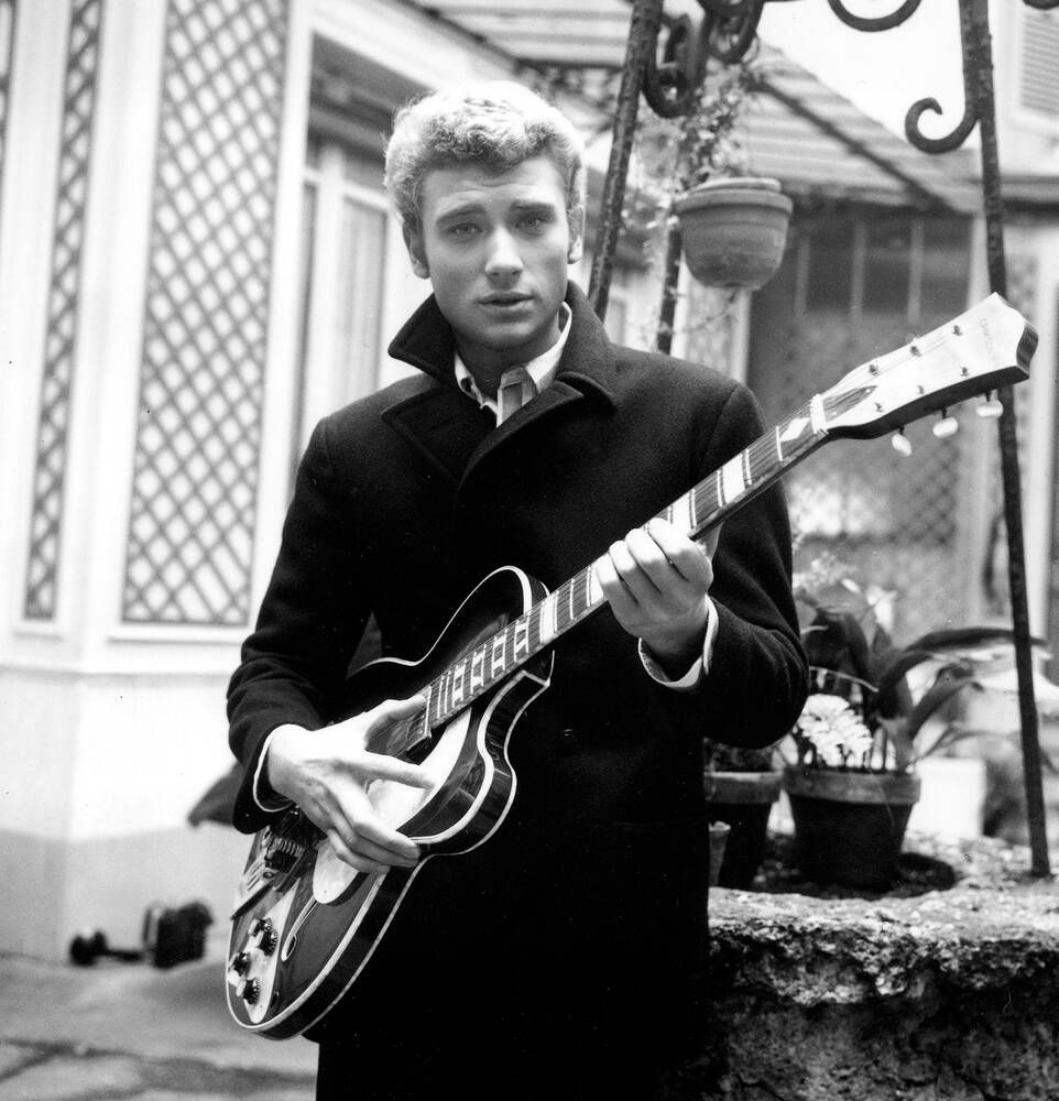 Een zwart-witfoto van een man die een gitaar vasthoudt.