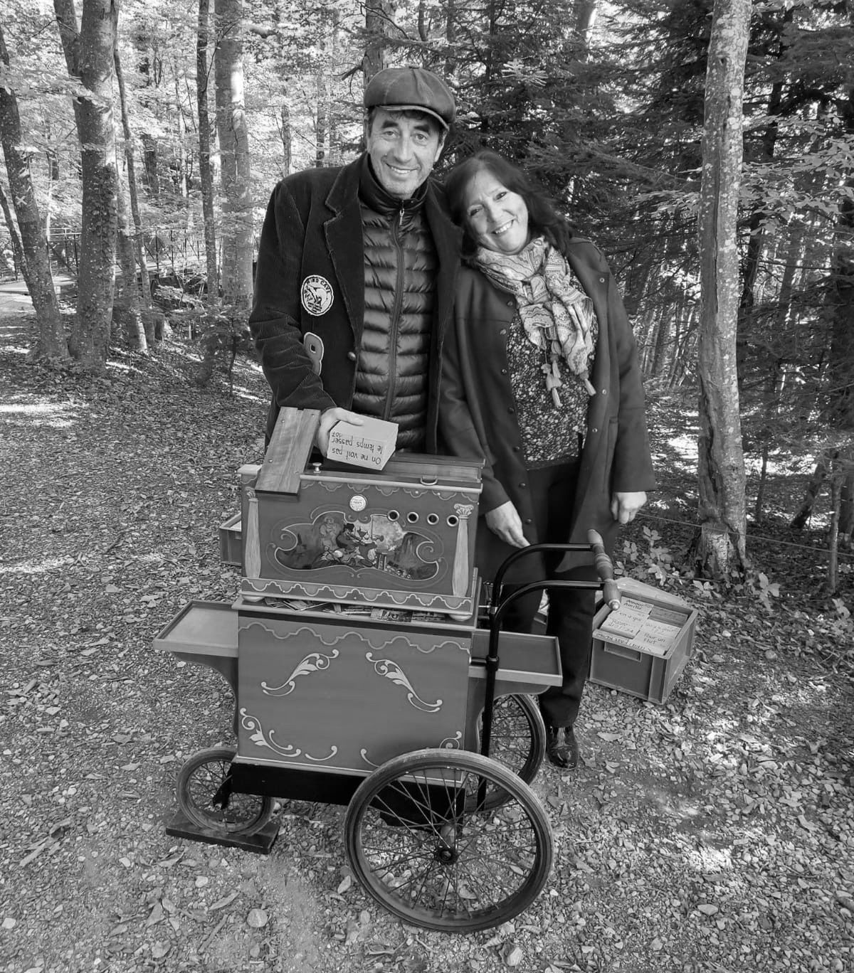 Een man en een vrouw staan ​​naast een kar in het bos.