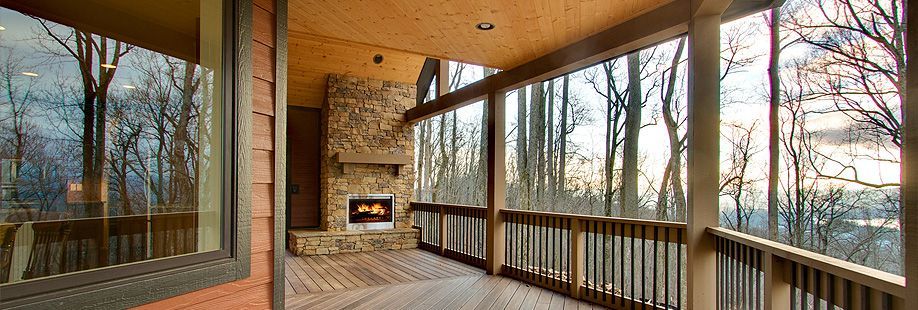 A screened in porch with a fireplace and trees in the background.