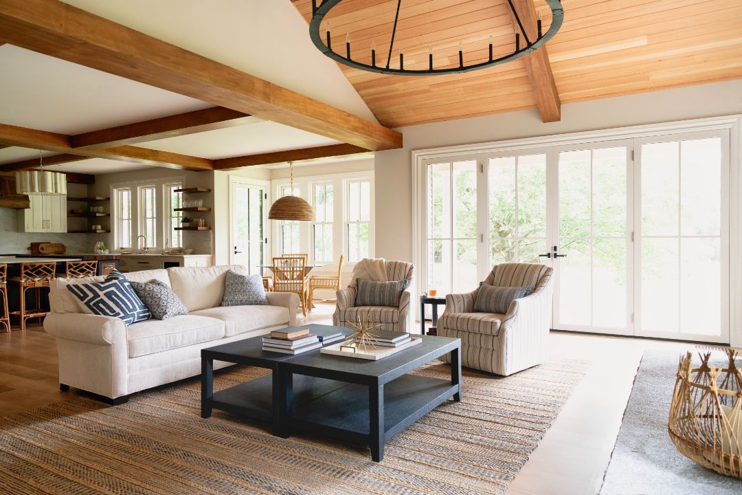 A living room with a couch , chairs , coffee table and lots of windows.