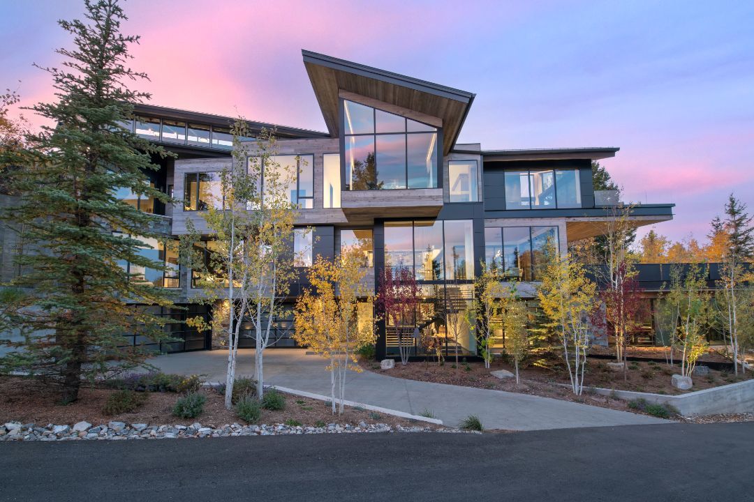 A large modern house with a lot of windows and trees in front of it.