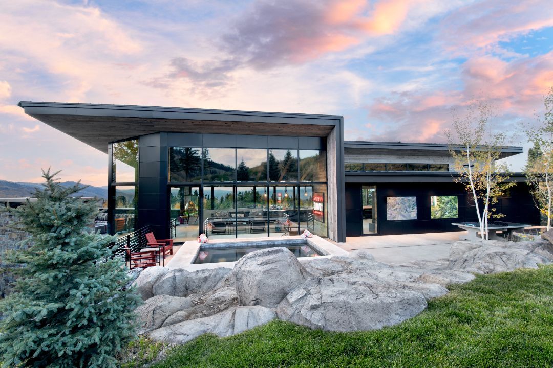 A modern house with a large window and a pool in the backyard.