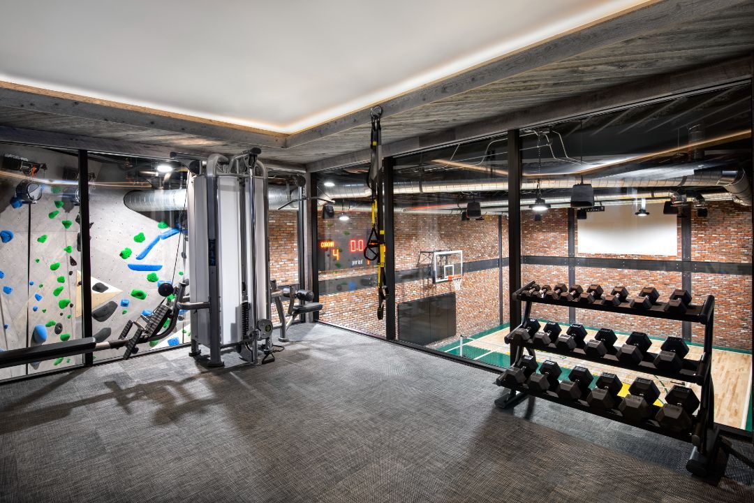 A gym with a climbing wall and a lot of dumbbells.