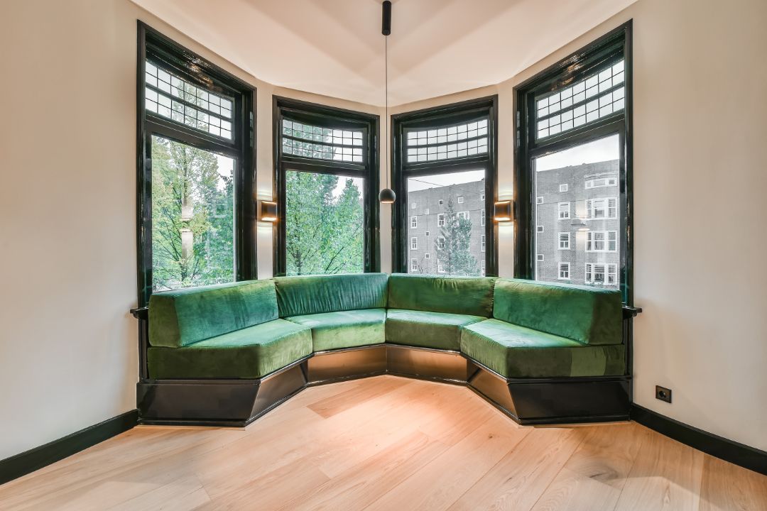 A living room with a green couch and lots of windows.