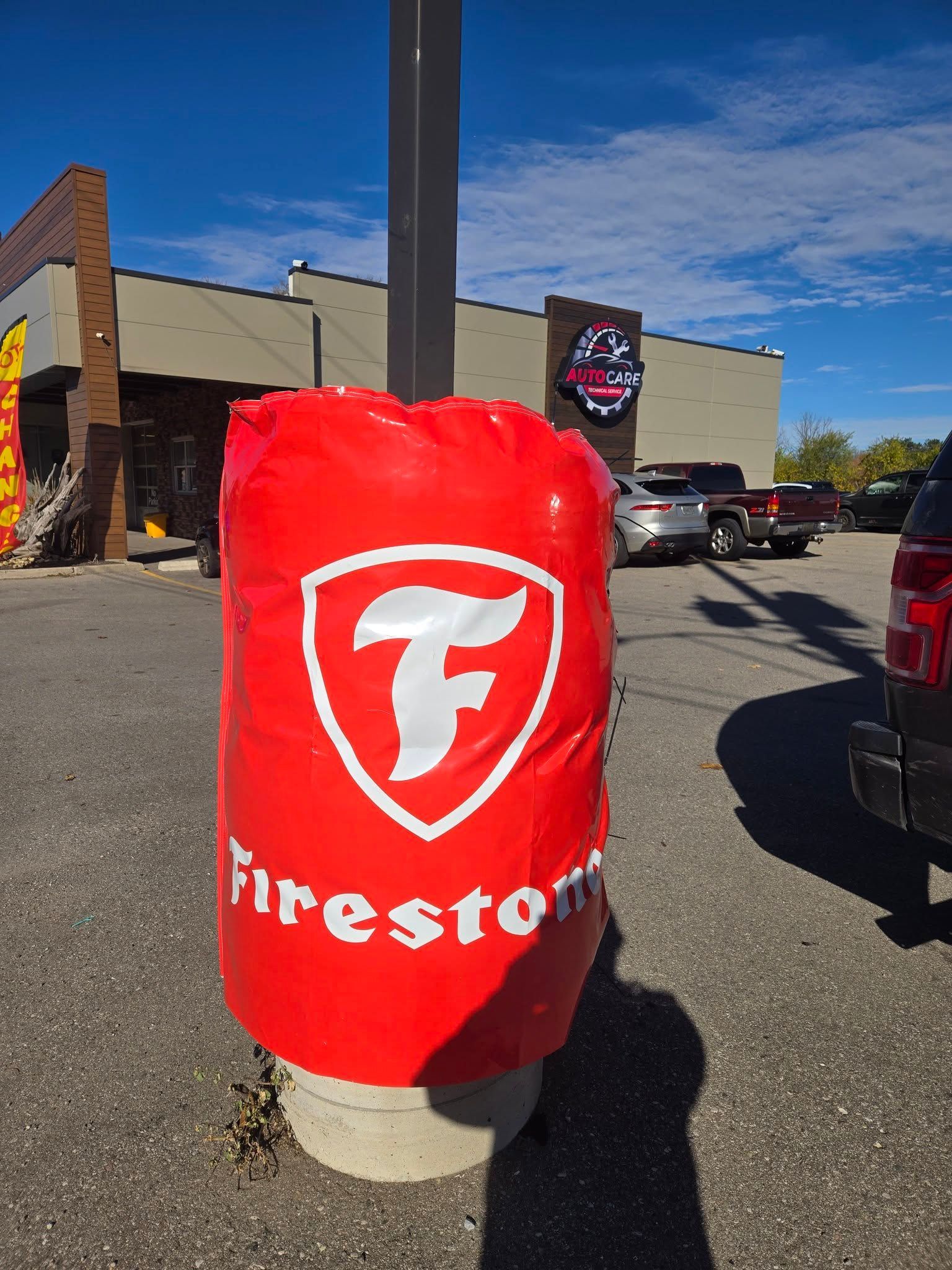 Red Firestone-branded cover on a post in a sunny parking lot outside a store | Auto Care Technical Services Inc.