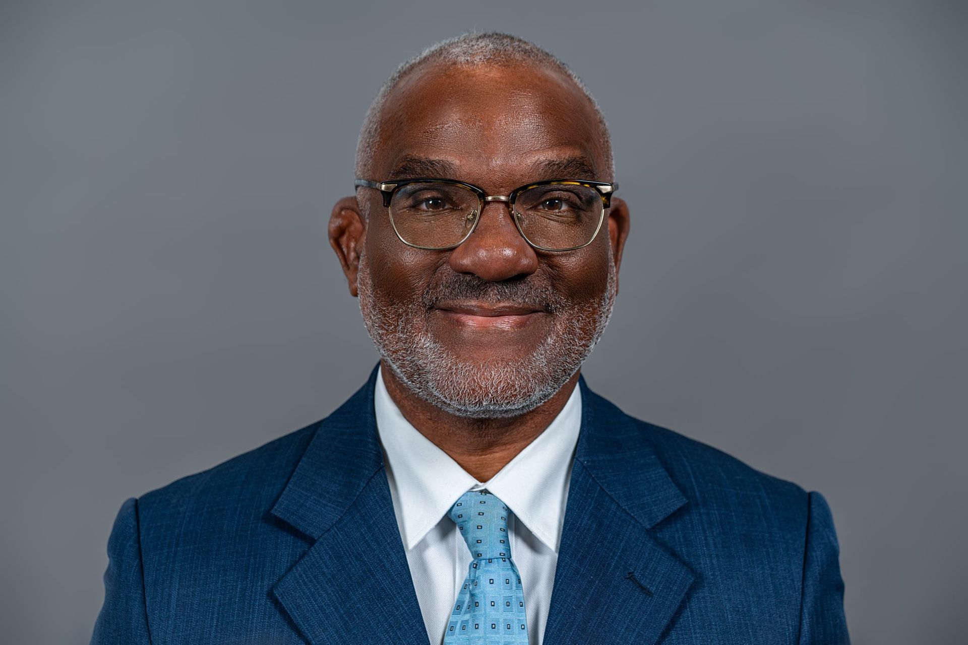 Close-up portrait of a smiling man in a suit and tie indoors.