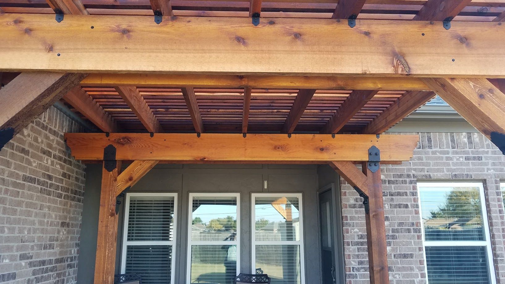 Wooden porch roof over brick entrance with double glass doors and windows