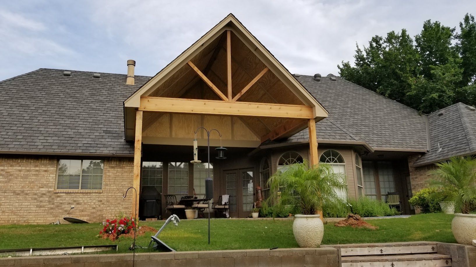 Stone house with a covered front porch, wooden gable roof, and landscaped lawn
