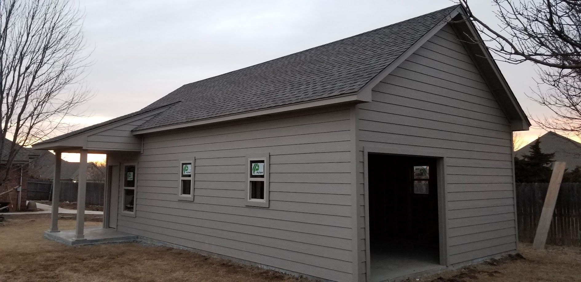 New beige house with dark roof and open garage in a rural setting