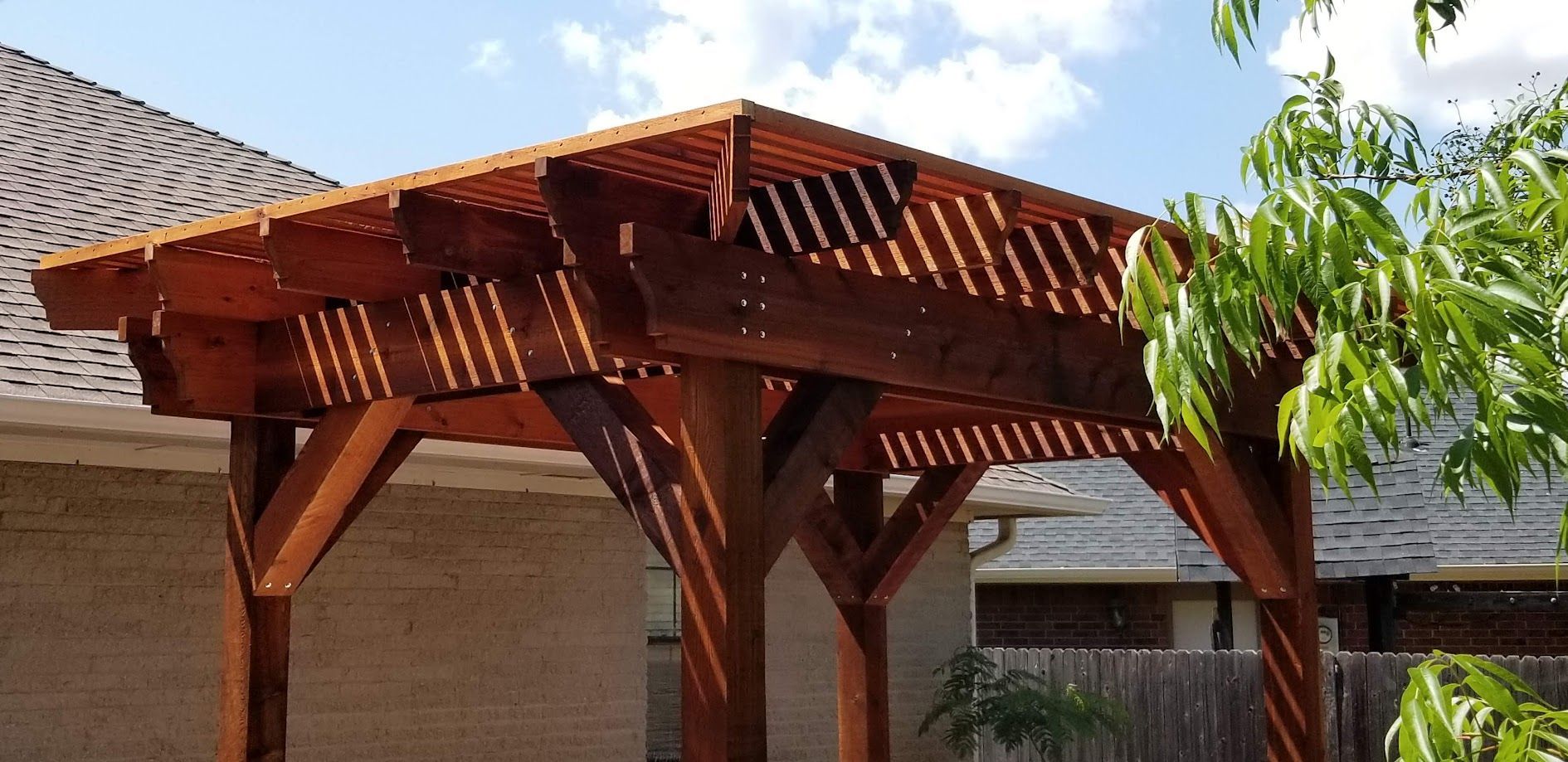 Wooden pergola structure with a slatted roof in a sunny backyard