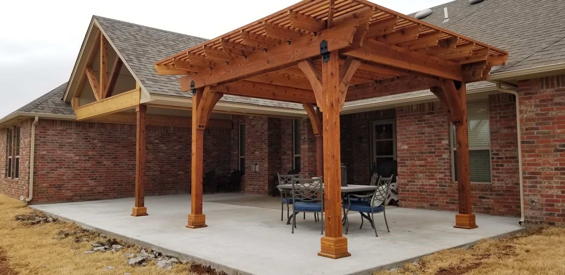 Brick house with a wooden pergola-covered patio and concrete porch area