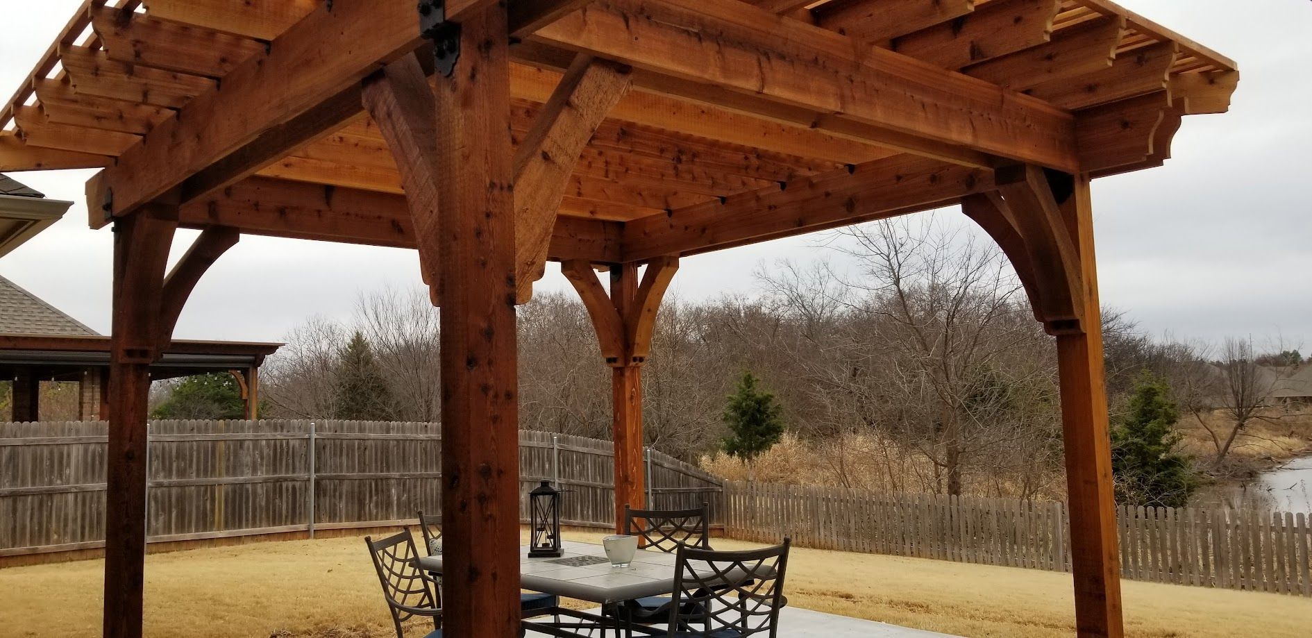 Wooden pavilion with picnic table in a dry, grassy park under an overcast sky