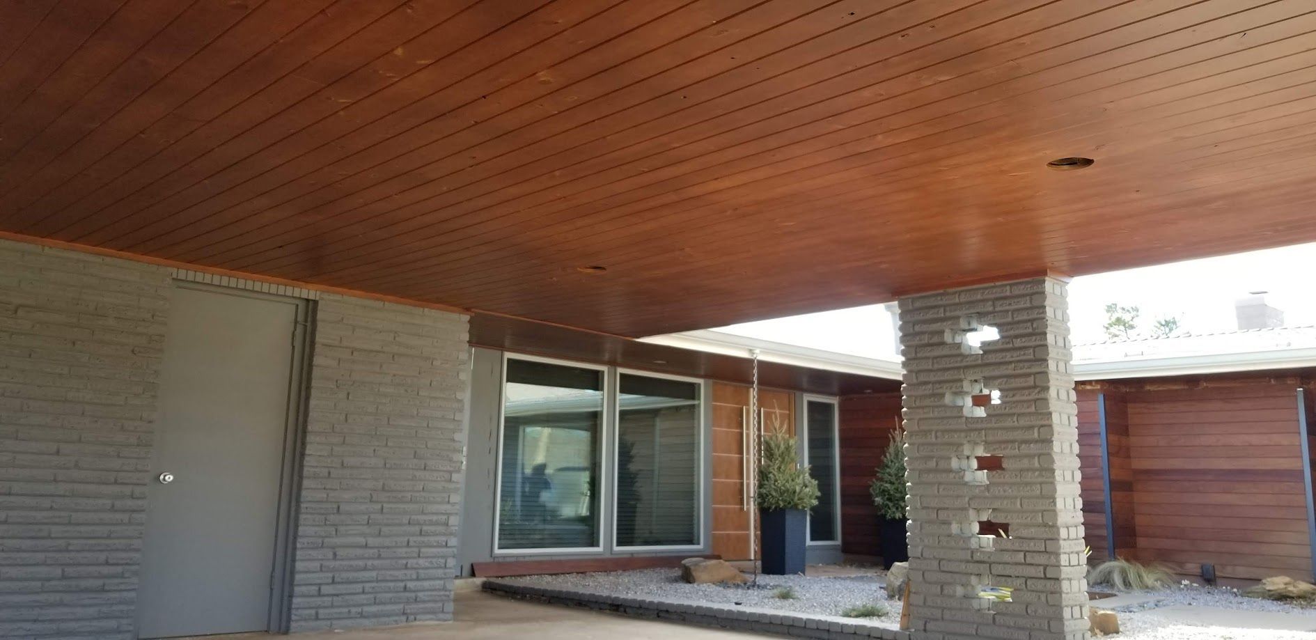 Covered front patio with brick columns, sliding glass doors, and a garage in the background