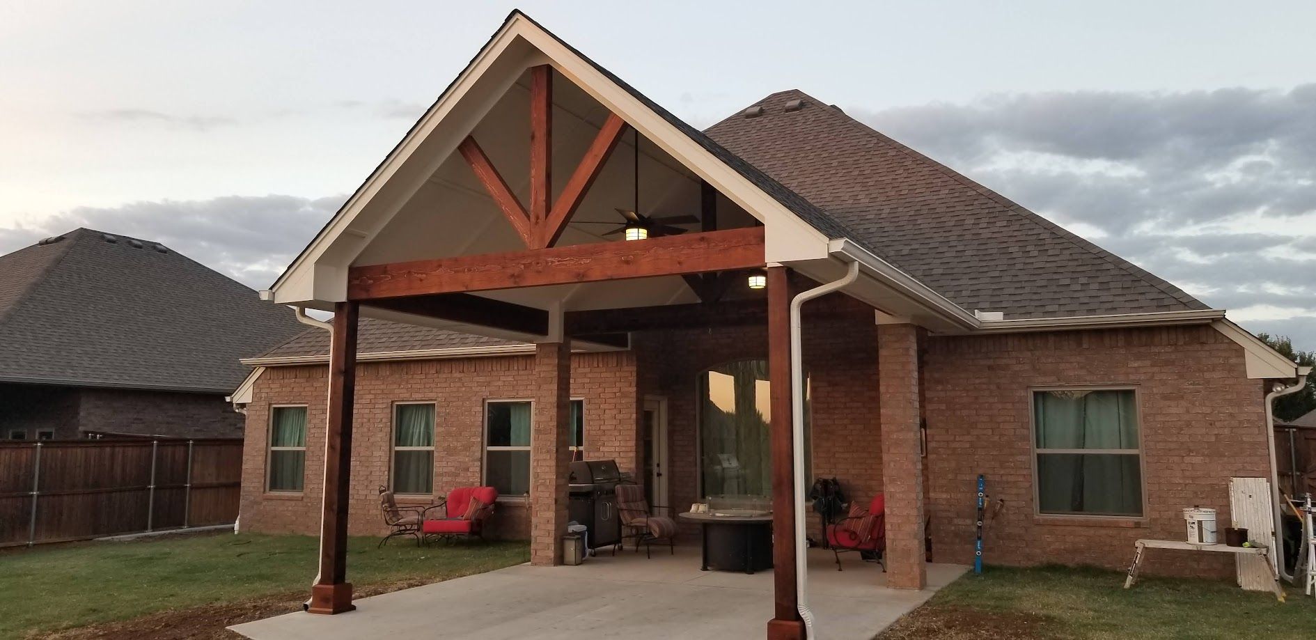 Brick house entrance with covered porch, wooden beams, and a paved driveway