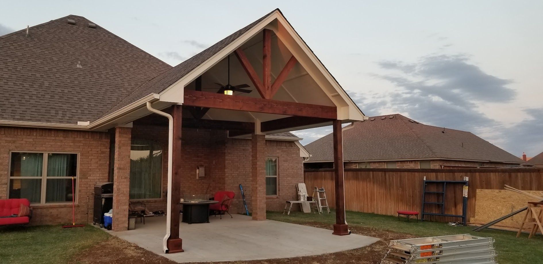 Brick house entrance with covered porch, red chairs, and a detached garage in a suburban yard