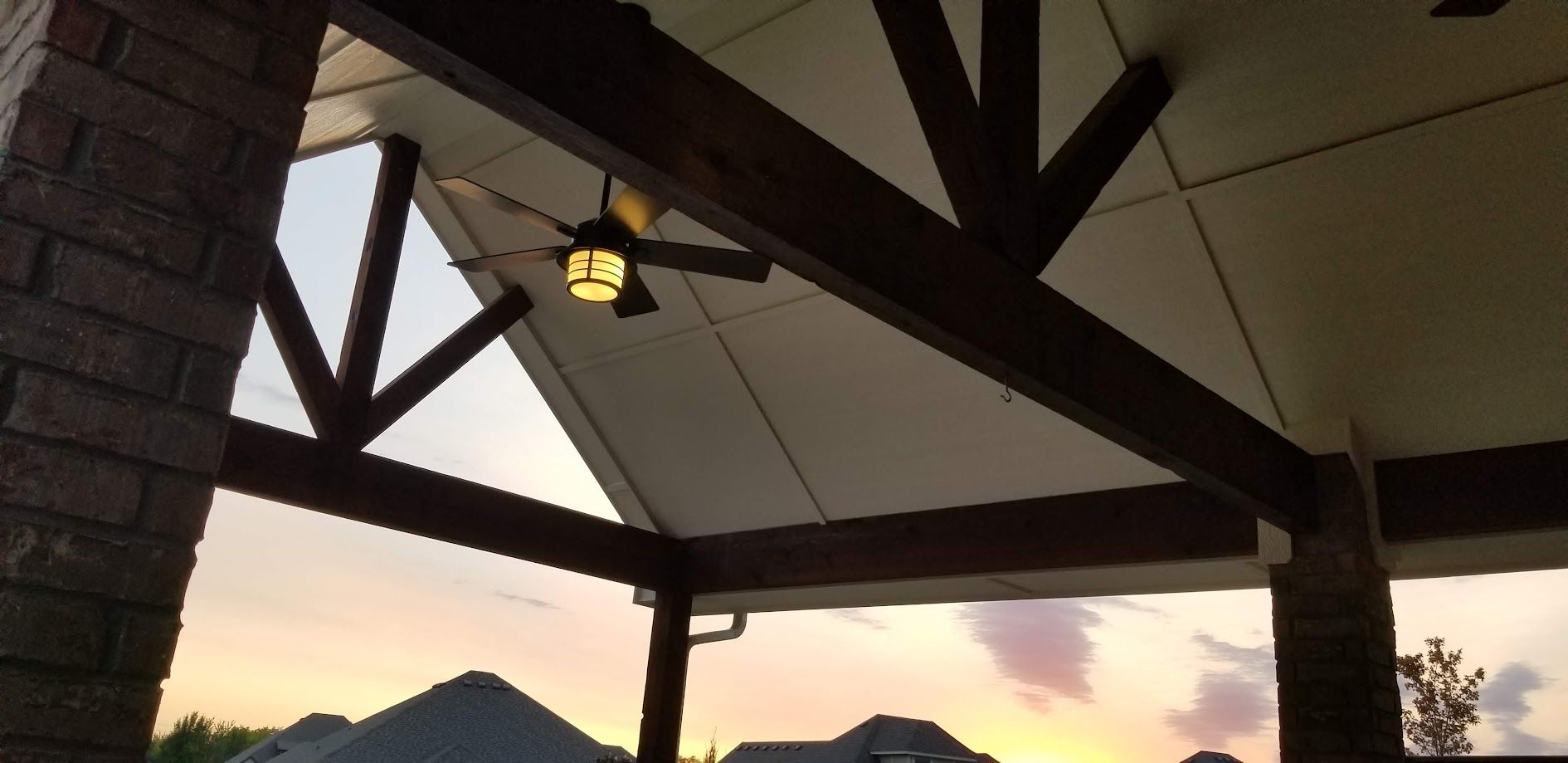 Patio roof beams and hanging lantern at sunset with mountains in the distance