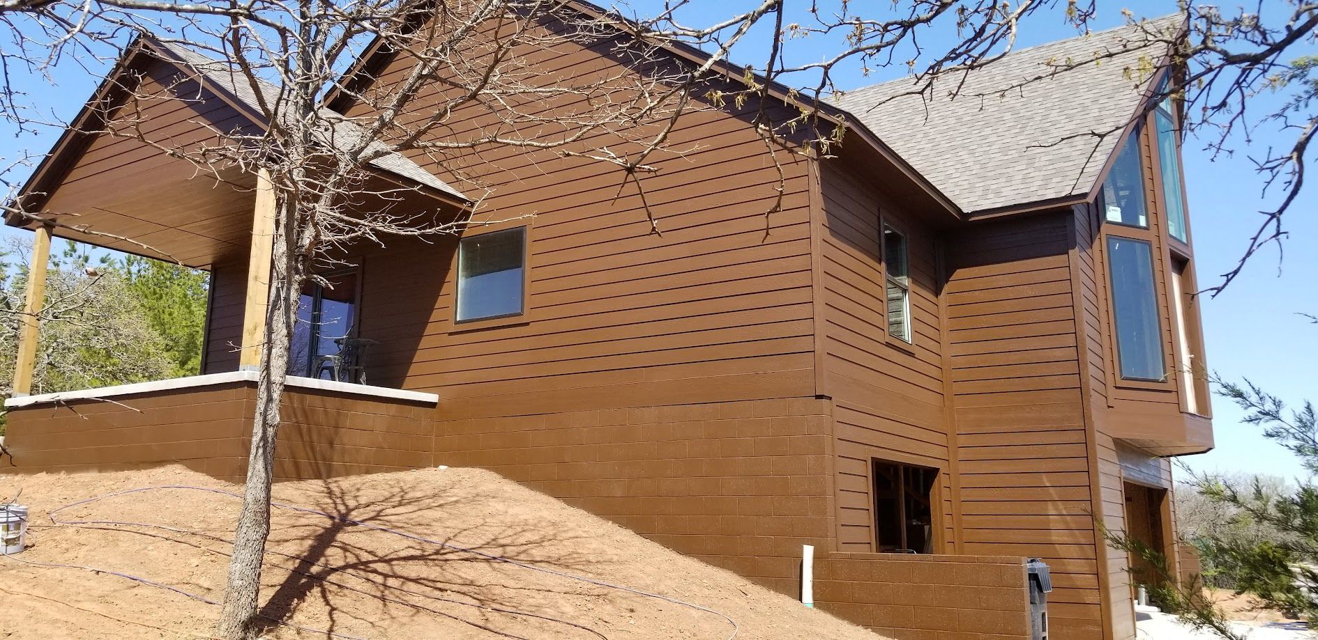Two-story brick house under construction with scaffolding and dirt mound in front