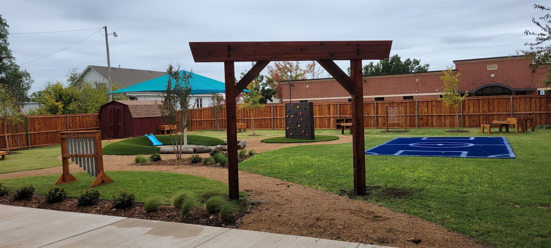 Backyard with pergola, lawn, patio, raised garden beds, and a blue trampoline under cloudy skies
