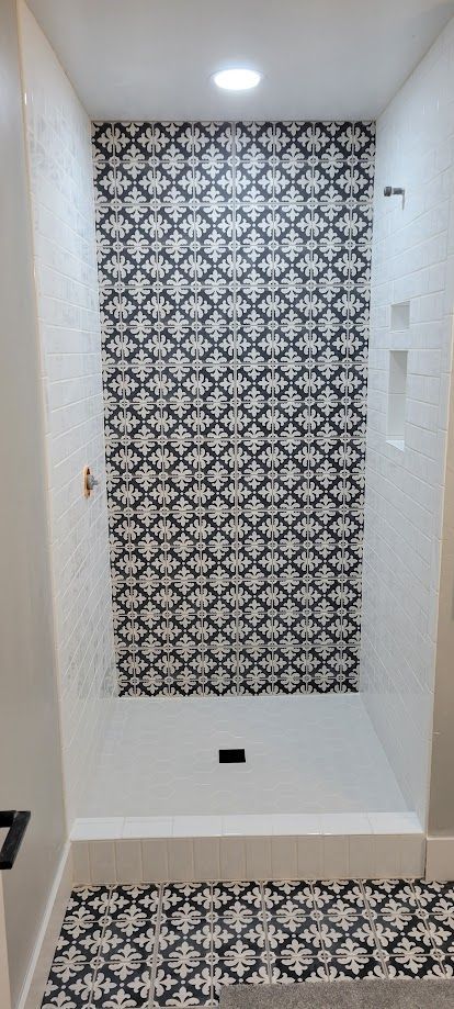 Wall niche with black-and-white patterned tile and a matching tiled floor section under recessed lights